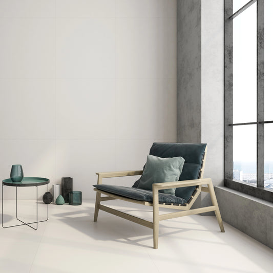 Argenta Cerámica Carpenter 'Albar', crèmekleurige vloer- en wandtegels in een loft met houten fauteuil bij een hoog raam