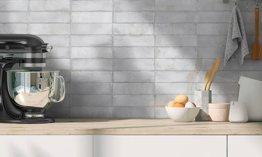 Estudio Cerámico Hackney 'Pearl', lichtgrijze wandtegels als spatwand in een keuken met houten blad en zwarte keukenmachine