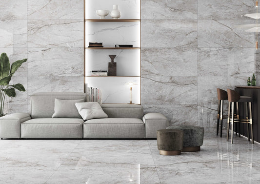 Keraben Idyllic 'Oxford Grey', lichtgrijze marmerlook vloer- en wandtegels in een woonkamer met lichte bank en wandnissen
