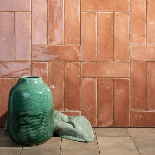 Estudio Cerámico Matcha 'Coral', zalmroze glanzende wandtegels staand en liggend in blokken gelegd met een groene vaas