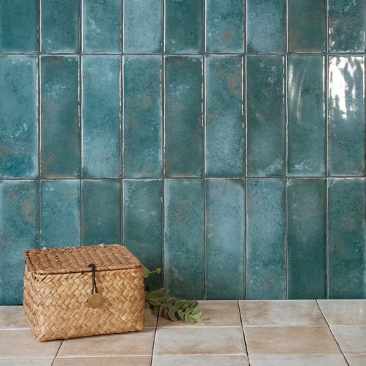 Estudio Cerámico Matcha 'Emerald', petrolblauwe glanzende wandtegels verticaal gelegd met een rieten mand op een tegelvloer