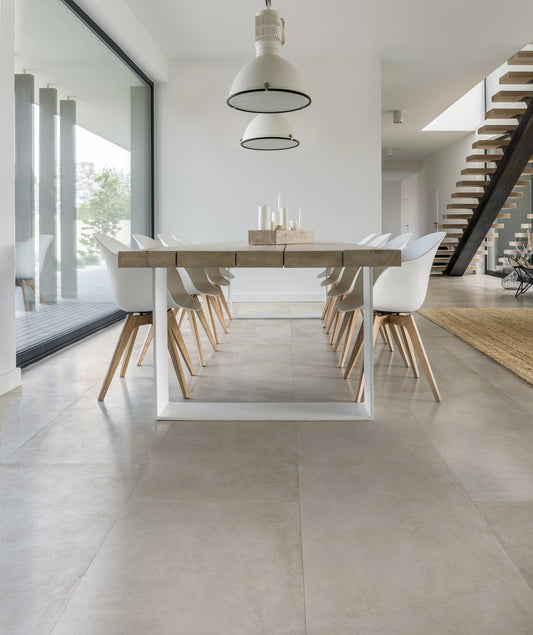 EnergieKer Parker 'White', crèmewitte betonlook vloertegels in een eetkamer met lange houten tafel en zwevende trap
