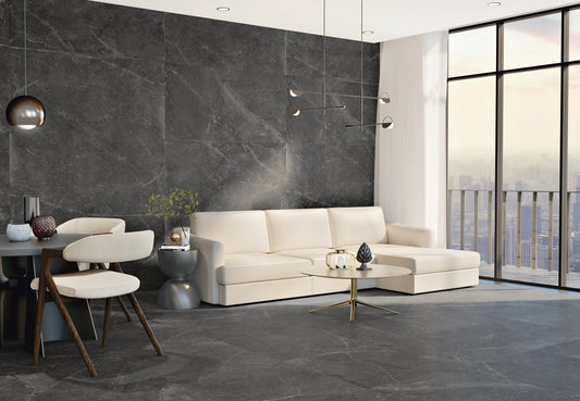 Azulejos Benadresa Pietra Antica 'Nero', antracieten marmerlook tegels in een woonkamer met witte hoekbank en groot raam