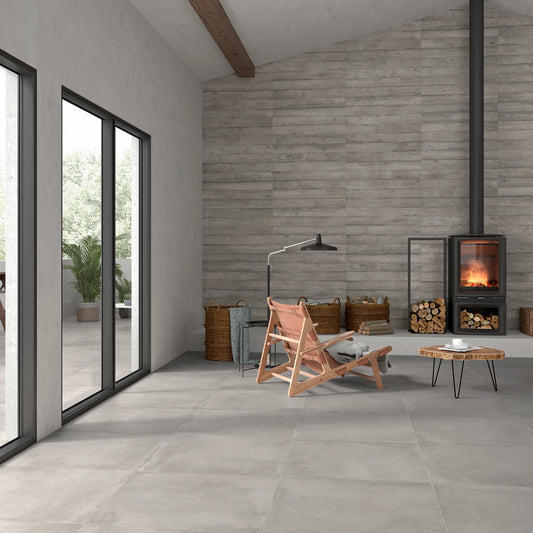 Argenta Cerámica Powder 'Argent', beige-grijze vloertegels 75x75 bij een houtkachel met loungestoel en boomstamtafel