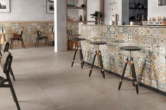 Ceramica Valsecchia Recover 'Beige', beige betonlook vloertegels in een café met een bar van kleurrijke patroontegels