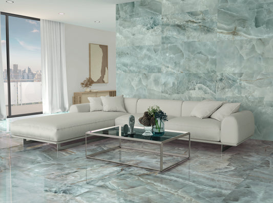 Azulejos Benadresa Saphire 'Jade', groengrijze marmerlook wandpaneel in een woonkamer met witte hoekbank en glazen salontafel