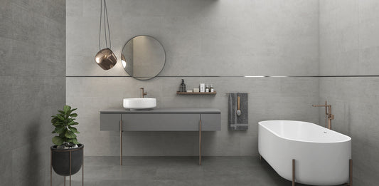 Argenta Cerámica Wave 'Resin Concrete', grijze betonlook wandtegels in een badkamer met bad, spiegel en wastafelmeubel
