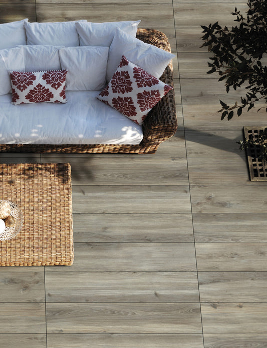 EnergieKer Woodbreak 'Hemlock', grijze houtlook vloertegels op een terras met rieten loungebank, van bovenaf gezien