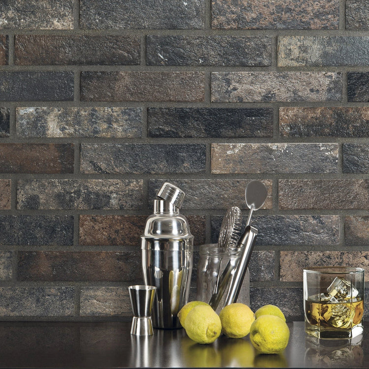 Ceramica Rondine Bristol, donkere baksteenlook wandtegels achter een bar met cocktailshaker, citroenen en een whiskyglas