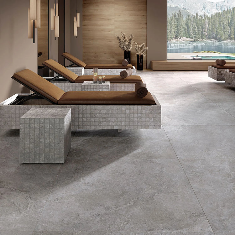 Tuscania Dolomia Stone, grijze vloertegels in een wellnessruimte met ligbedden en uitzicht op een bergmeer