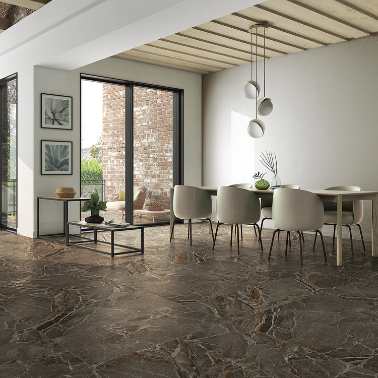 La Platera Dusk, taupe marmerlook vloertegels in een open eethoek met witte stoelen, hanglampen en een bakstenen pui
