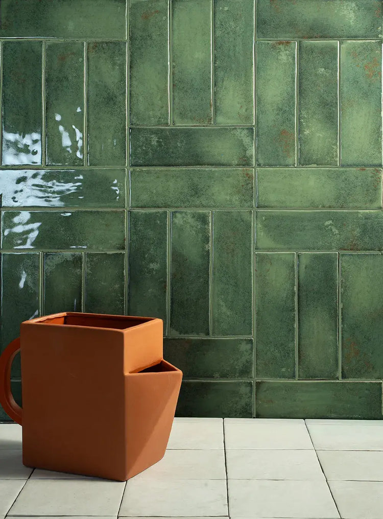 Groene glanzende wandtegels met een terracotta plantenbak ervoor