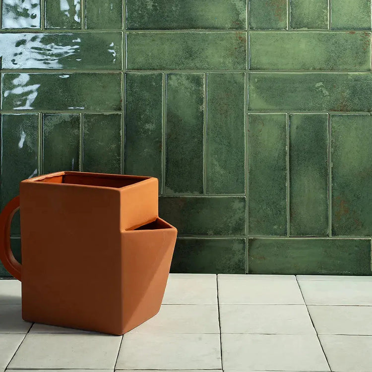 Groene glanzende wandtegels met een terracotta plantenbak ervoor