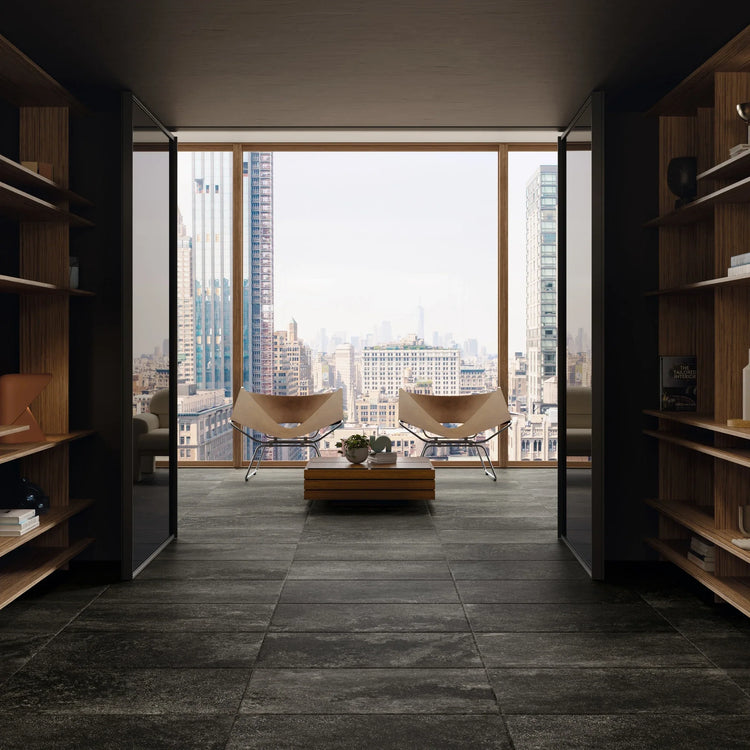 Ceramica Gazzini Lava Stone, zwarte vloertegels in een gang met houten boekenkasten en uitzicht op de skyline