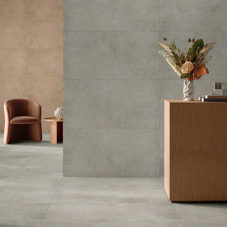 EnergieKer Miro, grijze vloer- en wandtegels in een lounge met terracotta fauteuil, zandkleurige wand en houten dressoir