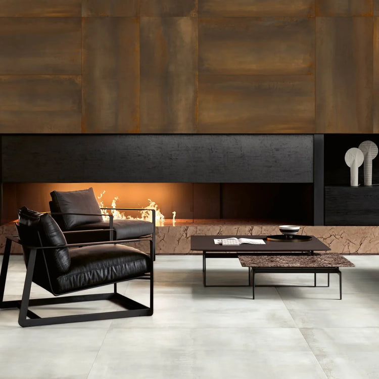 EnergieKer Oxidatio, roestbruine metaallook wand boven een open haard in een woonkamer met zwarte leren fauteuils