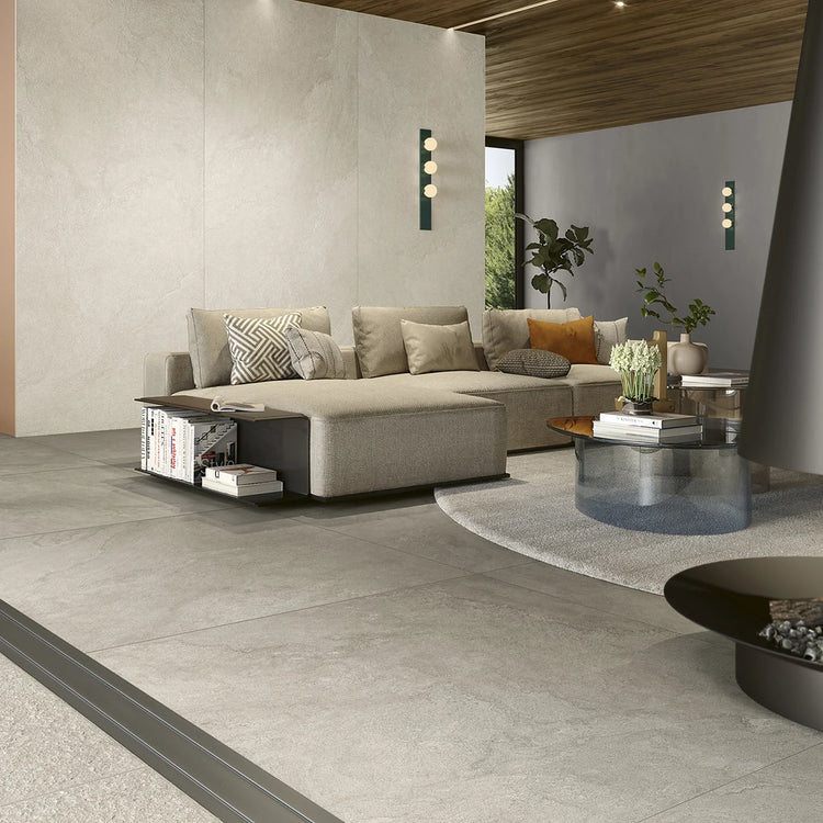 Lea Ceramiche Pulse 'Clay', taupe natuursteenlook vloer in een woonkamer met beige hoekbank en glazen salontafel