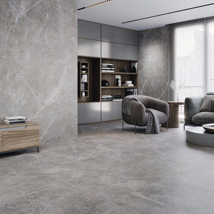 Grijze betonlook vloertegels in een moderne woonkamer met grote raampartij en zithoek