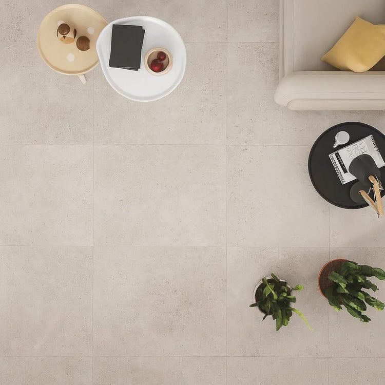 Tikal van Cerpa Cerámica, beige betonlook vloertegels van bovenaf met een tafeltje en planten
