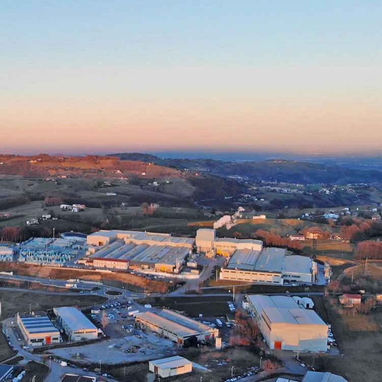 Tuscania fabrieksterrein vanuit de lucht bij zonsondergang, met heuvels erachter