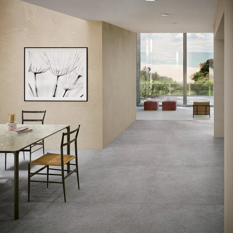 Grote grijze vierkante vloertegels in een modern, licht interieur met eethoek
