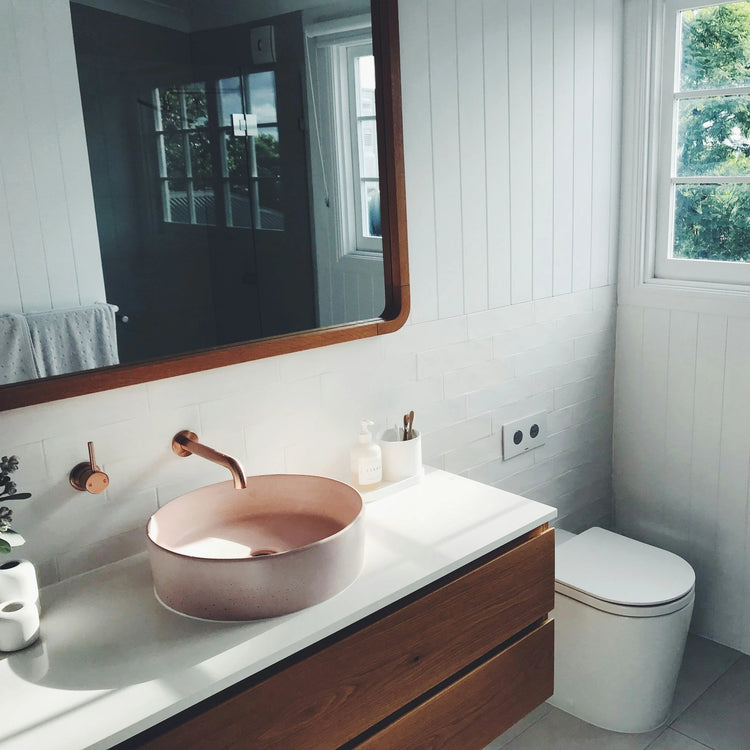 Vintage badkamer met witte lambrisering, ronde spiegel en terracotta waskom