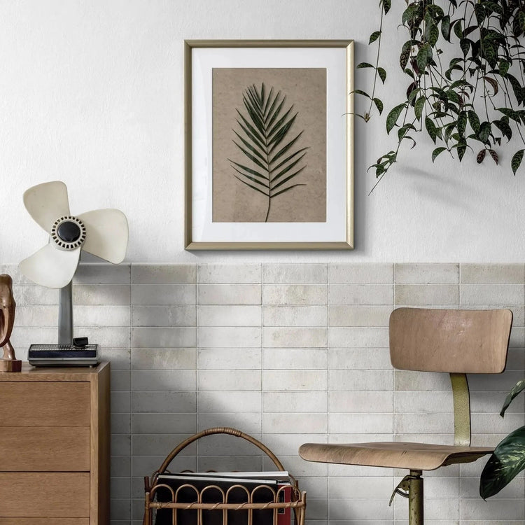 Witte handvormlook wandtegels in een woonkamer met ingelijste poster en ventilator