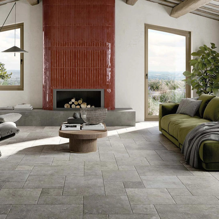 Ceramica Rondine Windsor, grijze vloertegels in modulair verband in een woonkamer met rode haard en groene bank