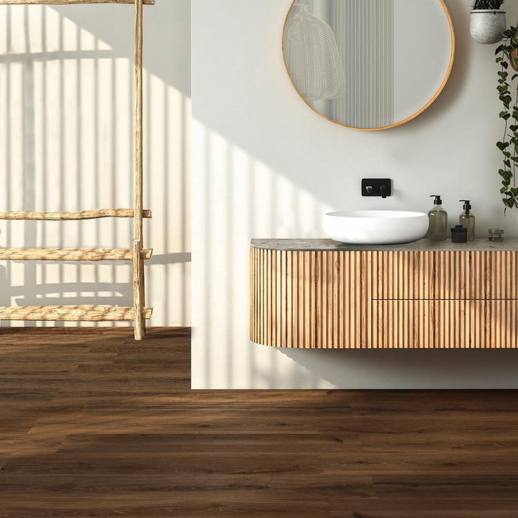 Woodbreak van EnergieKer, donkere houtlook vloertegels in een badkamer met ronde spiegel