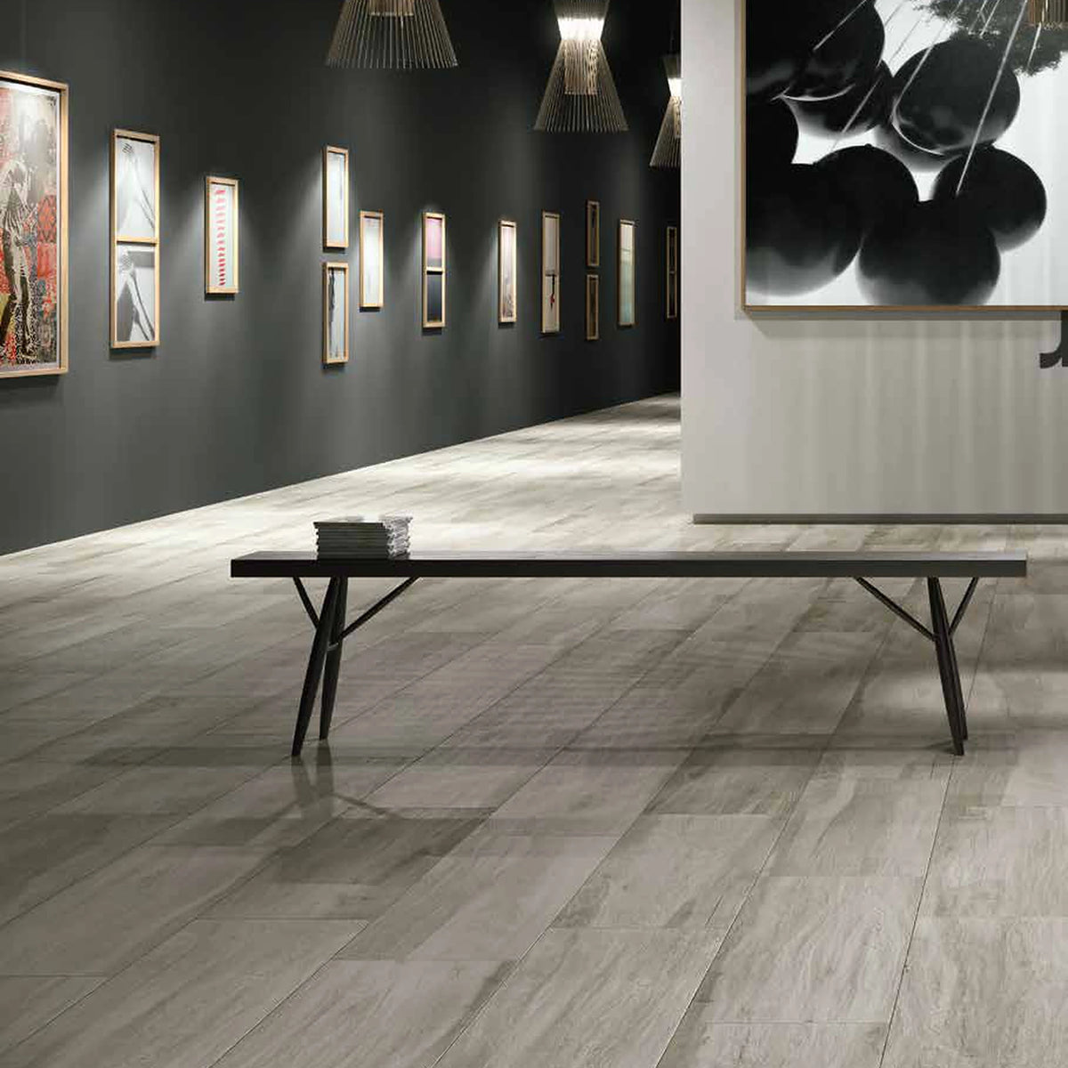 Castelvetro Aequa 'Cirrus Grip', grijze houtlook vloertegels, hier 30x120cm, in een galerie met donkere wanden en zwarte bank