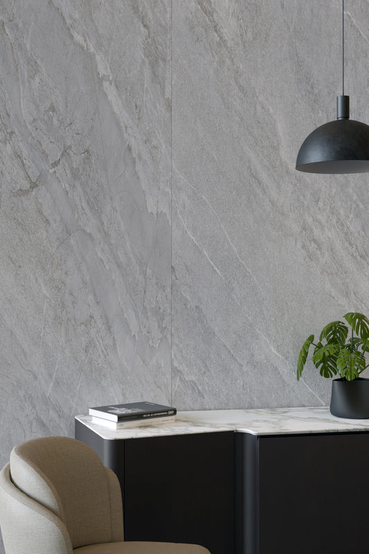 EnergieKer Agathòs 'Grey', grijze natuursteenlook wandtegels met diagonale nerf achter een zwart dressoir met plant