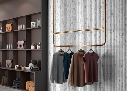 Estudio Cerámico Argos 'Statuario', witte marmerlook wandtegels met verticaal reliëf in een kledingwinkel met kledingrek