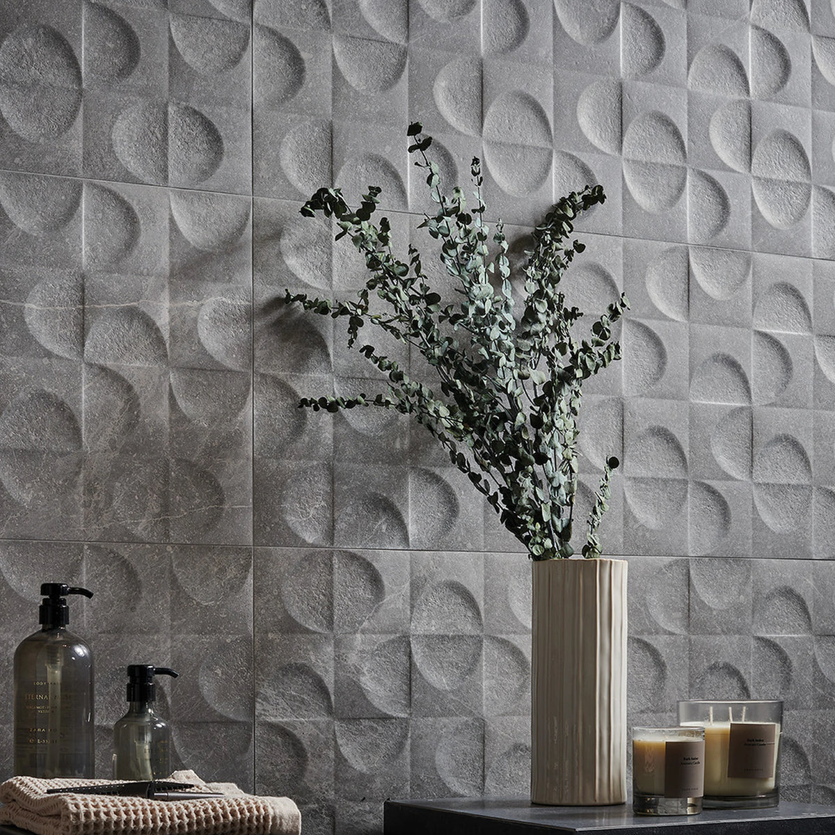 Keraben Bleuemix 'Grey', grijze wandtegels, hier met reliëf Concept, achter een vaas met eucalyptus