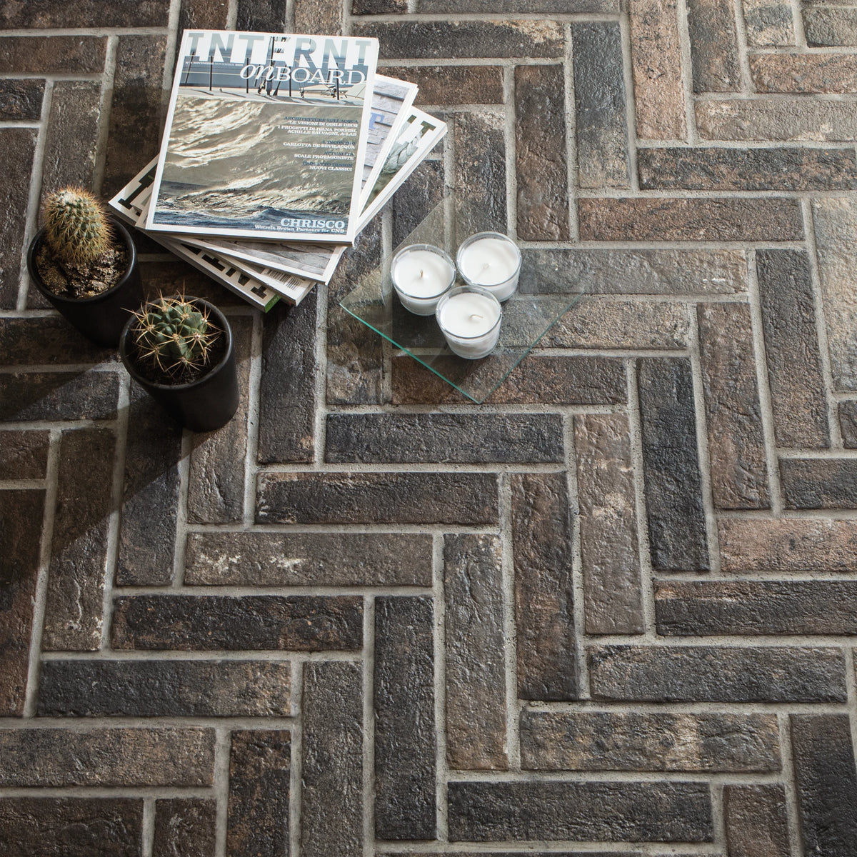 Ceramica Rondine Bristol 'Dark', donkere baksteenlook vloertegels in visgraatverband met tijdschriften en kaarsjes