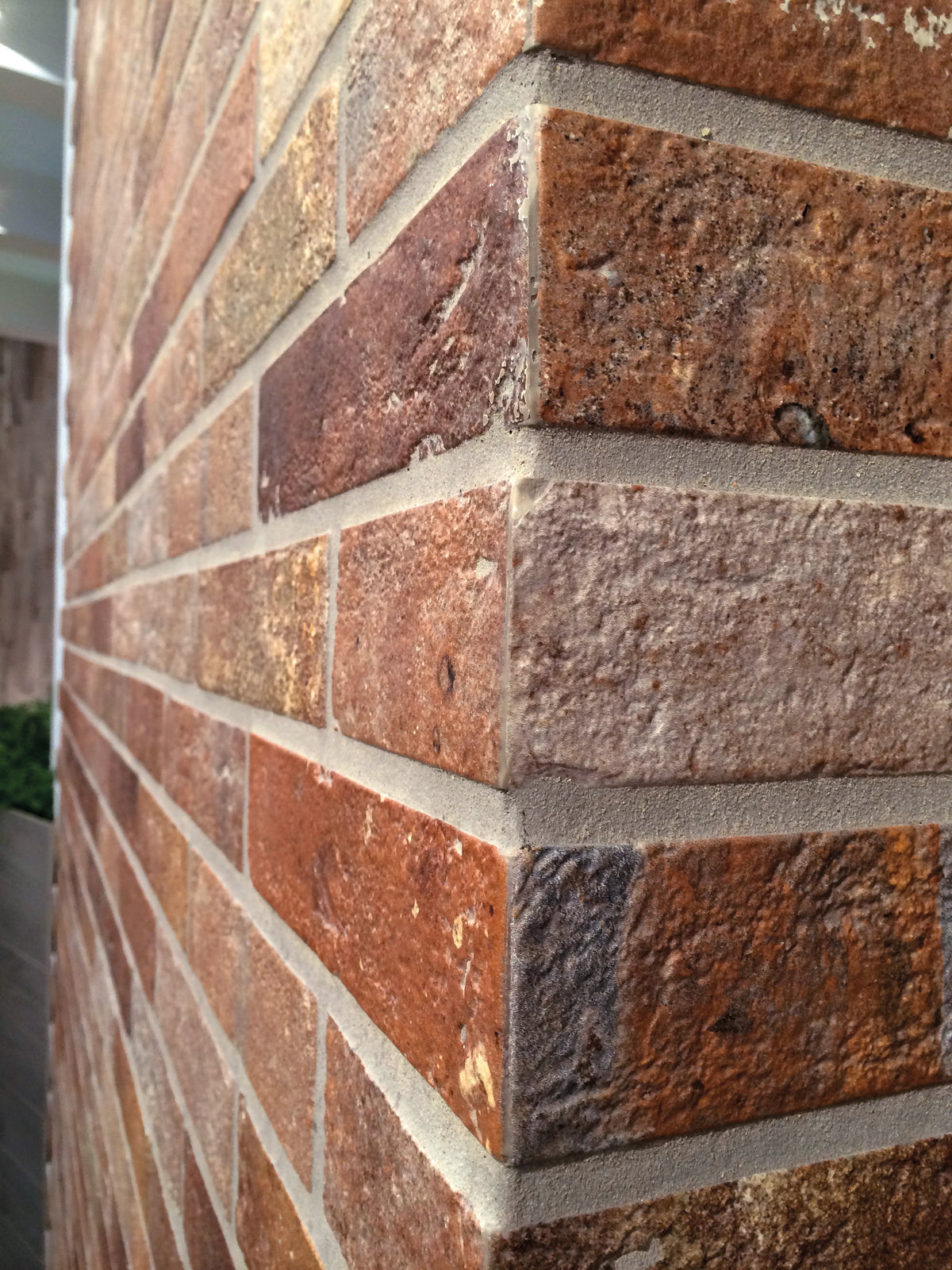 Ceramica Rondine Bristol 'Red', roodbruine baksteenlook tegels rond een buitenhoek, met lichte voegen in strijklicht