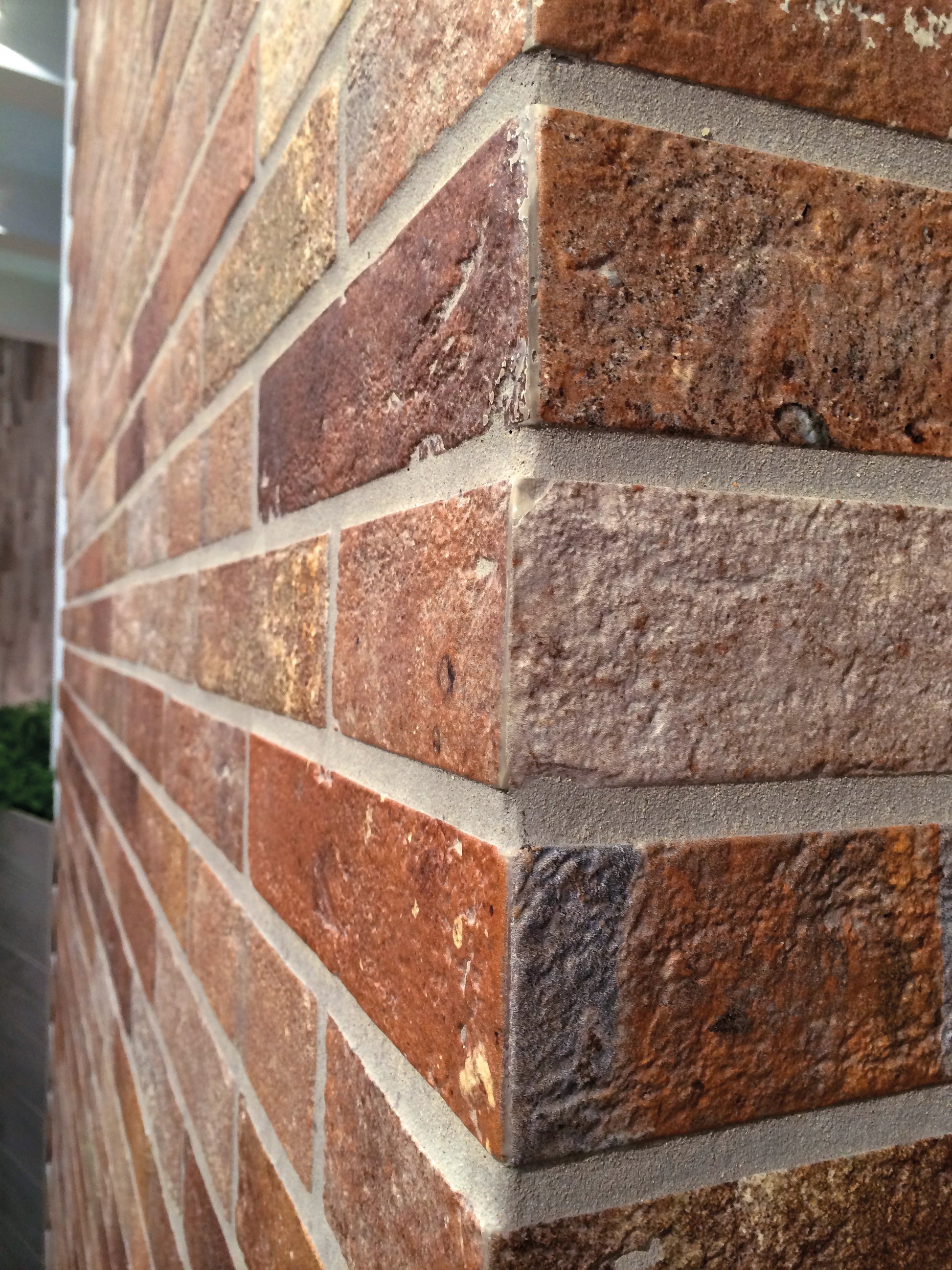 Ceramica Rondine Bristol 'Red', roodbruine baksteenlook tegels rond een buitenhoek, met lichte voegen in strijklicht