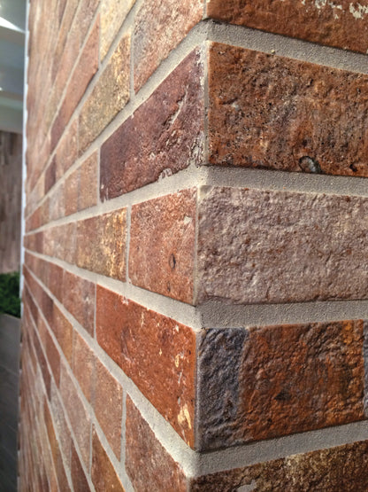 Ceramica Rondine Bristol 'Red', roodbruine baksteenlook tegels rond een buitenhoek, met lichte voegen in strijklicht
