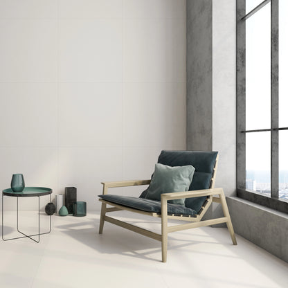 Argenta Cerámica Carpenter 'Albar', crèmekleurige vloer- en wandtegels in een loft met houten fauteuil bij een hoog raam