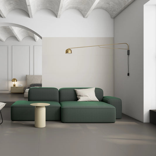 Argenta Cerámica Carpenter 'Grey', grijze vloertegels in een loft met gewelfd plafond, groene bank en gouden wandlamp
