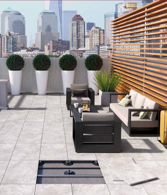Tuscania Dolomia Stone 'White', lichte natuursteenlook tegels op een dakterras met loungeset en uitzicht op de skyline