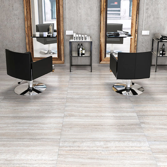 Tuscania Dolomia Stone 'White Vein Cut', lichte vloertegels met lengteaders in een kapsalon met zwarte stoelen en spiegels