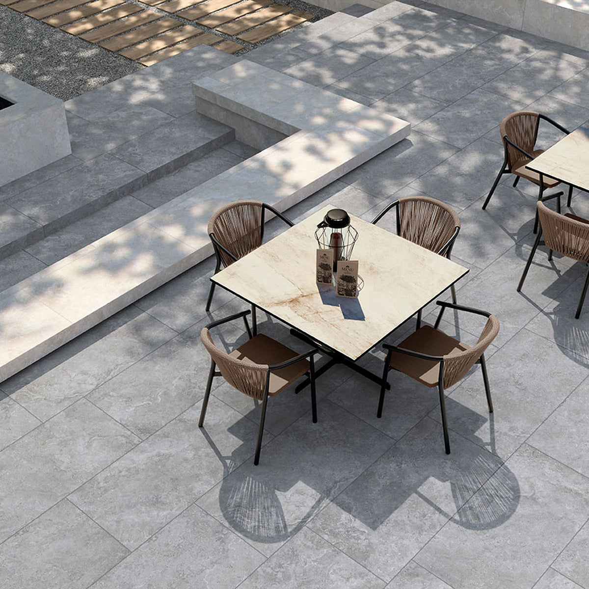 Tuscania Dolomia Stone 'Grey', grijze buitentegels, hier 2cm dik, op een terras bij een zwembad met rieten stoelen