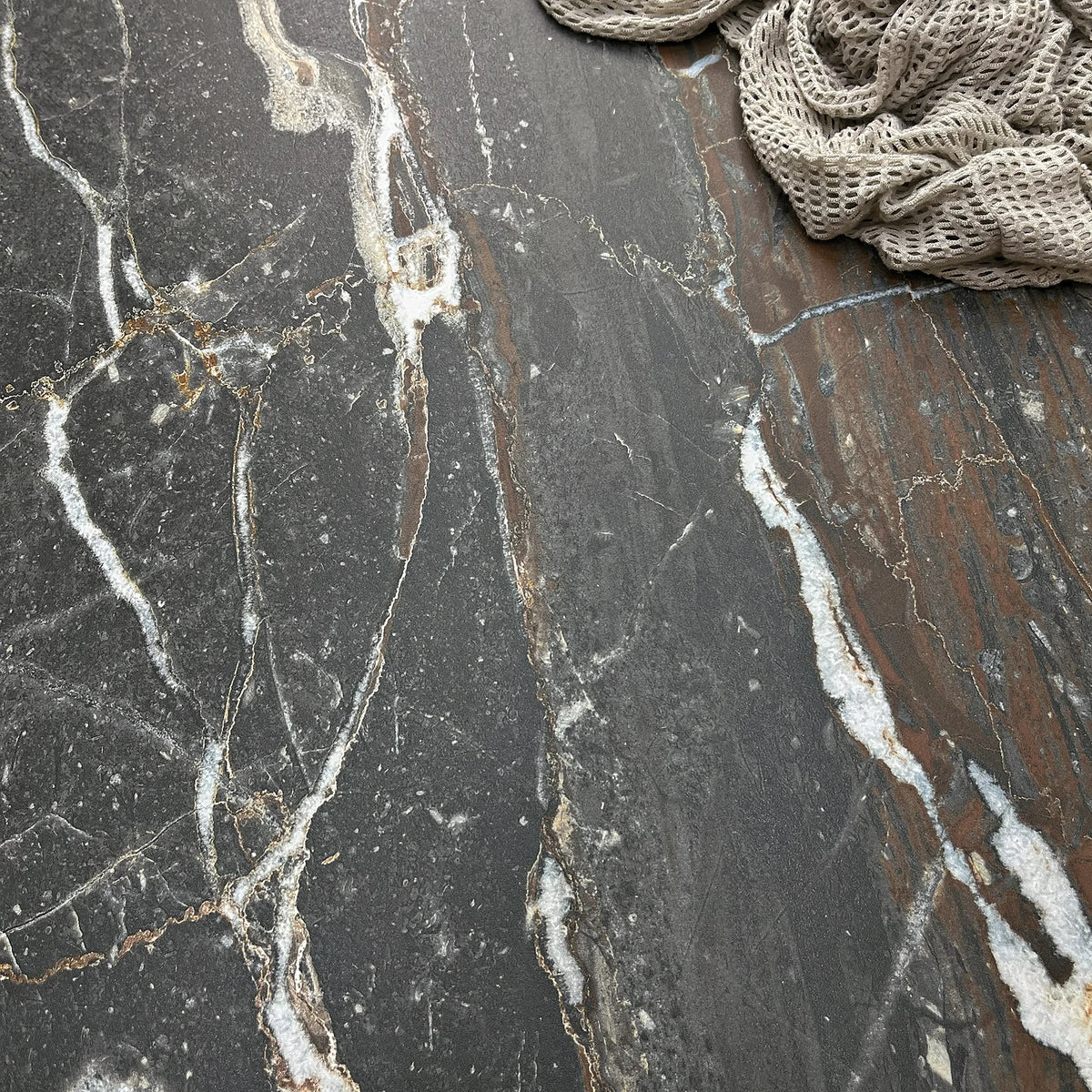 La Platera Dusk 'Black', detail van zwarte marmerlook tegel, hier 60x60cm, met witte en roestbruine aders