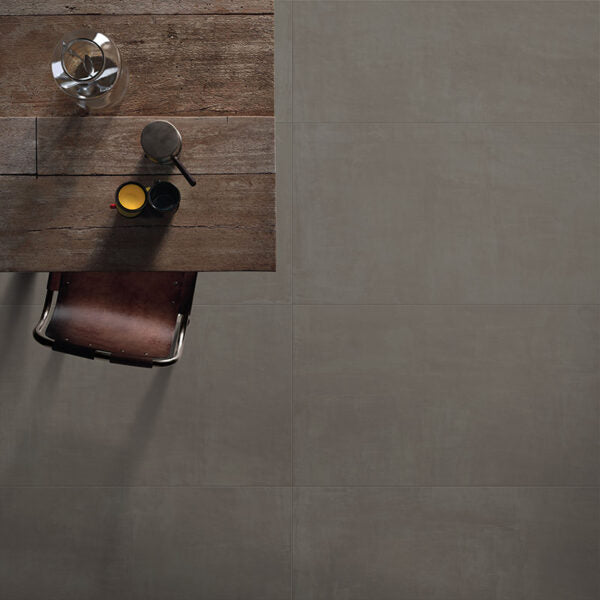 Ceramica Valsecchia Galaxy 'Dark', donkergrijze betonlook vloertegels van bovenaf naast een tafel met kopjes en leren stoel