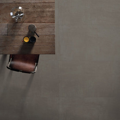 Ceramica Valsecchia Galaxy 'Dark', donkergrijze betonlook vloertegels van bovenaf naast een tafel met kopjes en leren stoel