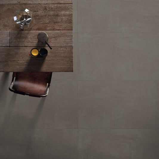 Ceramica Valsecchia Galaxy 'Dark', donkergrijze betonlook vloertegels van bovenaf naast een tafel met kopjes en leren stoel