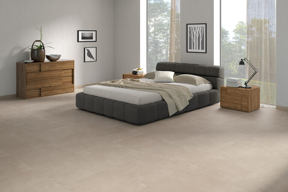 Ceramica Valsecchia Galaxy 'Beige', beige betonlook vloertegels in een slaapkamer met grijs bed en houten dressoir