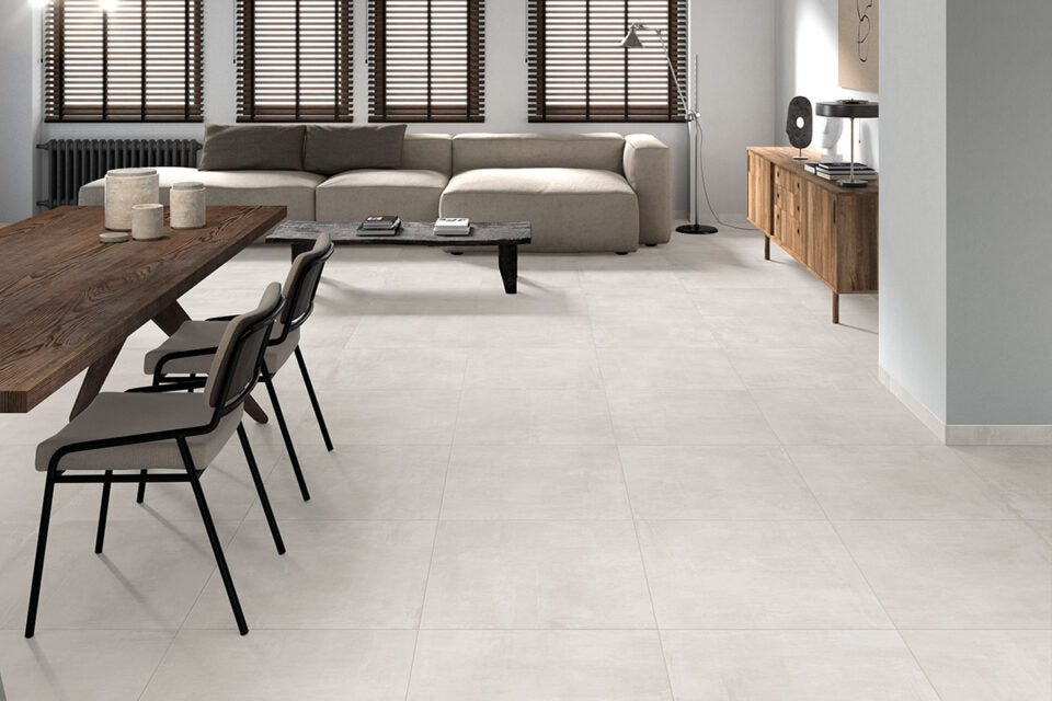 Ceramica Valsecchia Galaxy 'White', crèmewitte betonlook vloertegels in een woonkamer met houten eettafel en lichte bank