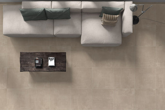 Ceramica Valsecchia Galaxy 'Taupe', taupe betonlook vloertegels van bovenaf met een lichte hoekbank en donkere salontafel