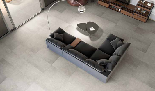 Tuscania Grey Soul 'Light', lichtgrijze betonlook vloertegels van bovenaf met een donkergrijze hoekbank en booglamp